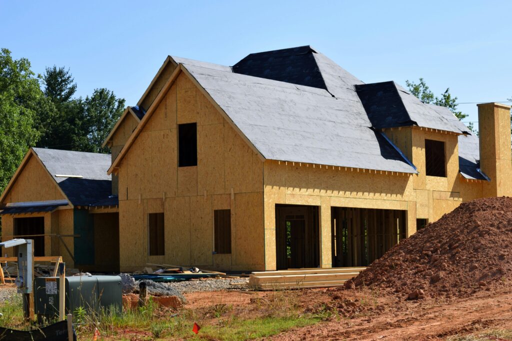 A partially built wooden house under construction, showcasing its progress and design in daylight.